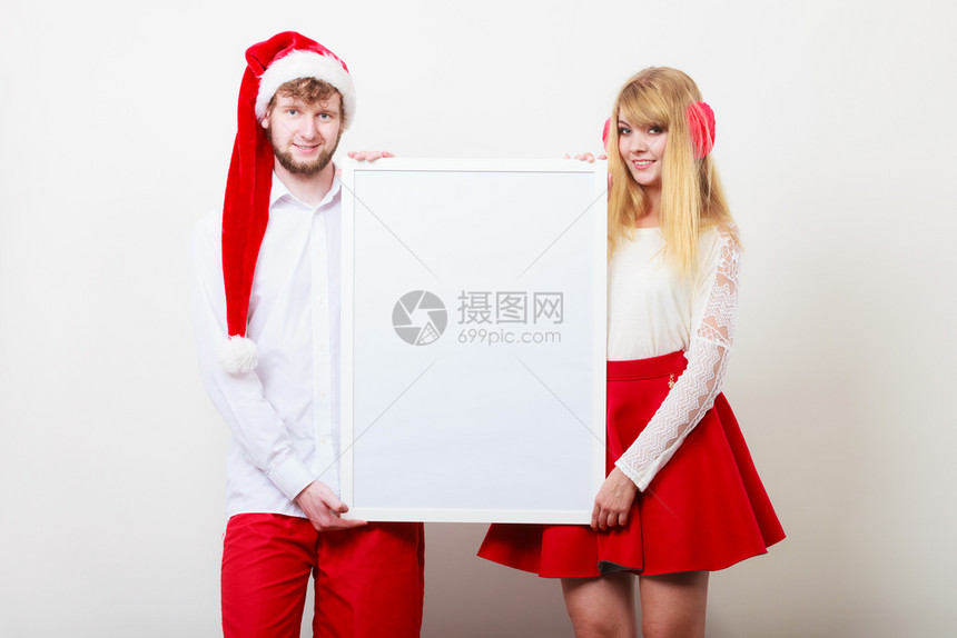 穿着圣达克萨斯帽的漂亮女孩和男人圣诞Xma广告带空白横幅的男女夫妇图片