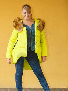美丽笑容的年轻时尚女孩穿着戴头罩的黄色外衣在冬季时装图片
