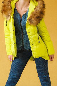 年轻时尚女孩穿着戴头罩的黄色外衣冬天时装图片