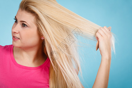 头发护理发型设计理念女人用梳子梳她的金色长发用梳子梳金色长发的女人图片