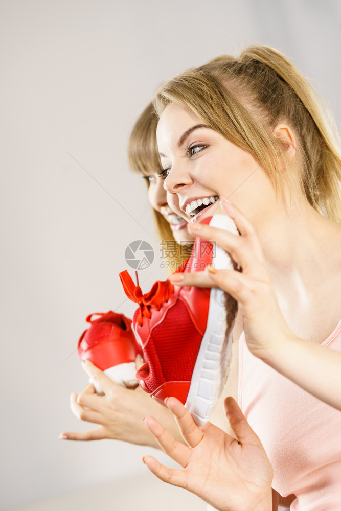 两个快乐的微笑体育女运动员展示鞋教练红舒适的合锻炼和训练图片