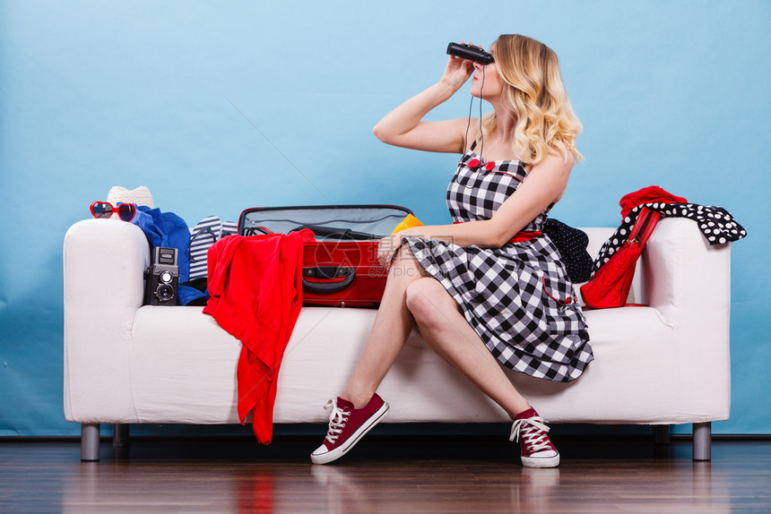 妇女透过望远镜看坐在沙发上拿着手提箱满的东西准备在暑假上取走图片