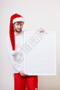 穿着圣达克拉斯帽的人拿着空的横幅上面有复制空间圣诞广告戴着塔帽的人上面有空白的横幅背景图片