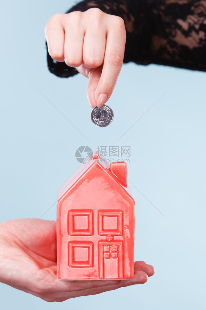 未来计划的储蓄人们手握着红色的小猪银行和币钱是家庭更好的生活人们手握着小房子和银币图片