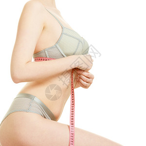 身穿内衣胸罩的瘦女人用红色的测量带被白色的侧面隔开胸部下方的测量图片