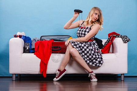 妇女拿着望远镜坐在沙发上拿着手提箱满的东西准备在暑假上取走图片
