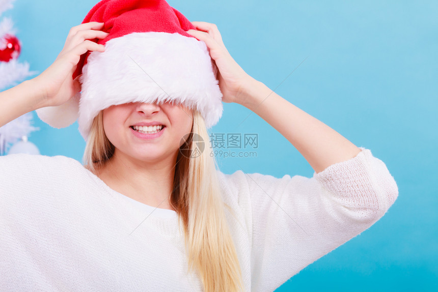 穿着圣诞快乐和欢概念戴圣诞老人帽子蒙着眼睛到处玩耍的妇女戴着圣诞老人帽子蒙着眼睛的妇女图片