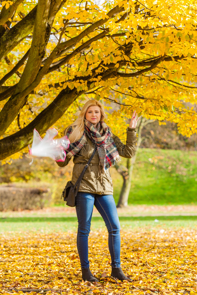 妇女带着伞在公园中行走秋天气明亮图片
