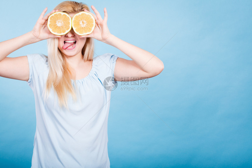 金发女少将两半黄葡萄果柑橘水握在手上蒙眼睛的蓝色健康饮食营养幸福的乐趣概念女孩用葡萄汁蒙在眼睛上图片
