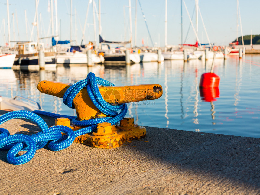 黄色系泊在船坞游艇上带蓝色绳子的黄系泊柱在背景中图片
