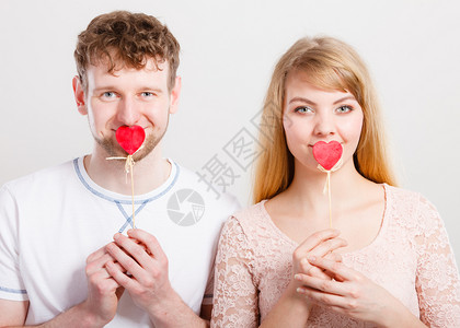 可爱的金发美女和男情人用小心棍子遮住他们的嘴图片