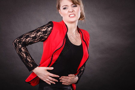 生病和疾健康问题的概念红衣女青年手抱在肚子的上因为剧烈的可怕痛苦背景图片