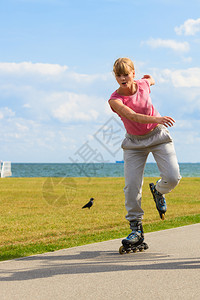 女孩独自在海边滑冰年轻的随身女士骑着滚动刀片独自在海边滑冰图片