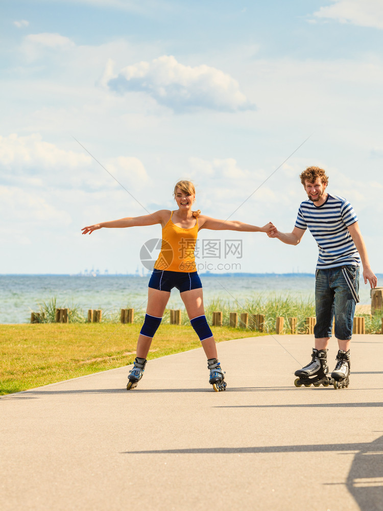 度假活跃的人和友谊概念穿滑溜冰雪的年轻情侣在海边户外玩滑雪冰男女在赛道上一起滚车图片