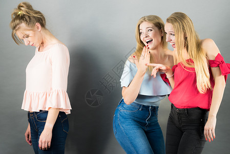 一个女人被两个女朋友欺负说她的闲话友谊是竞争和嫉妒的问题被两个女人说闲话的女人背景图片