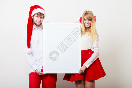 穿着圣达克萨斯帽的漂亮女孩和男人圣诞Xma广告带空白横幅的男女夫妇背景图片