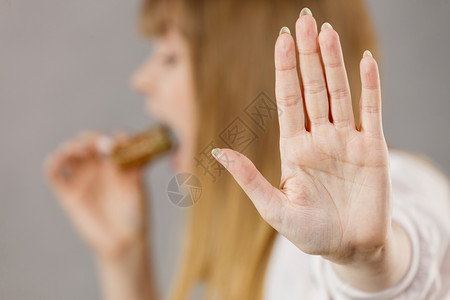 年轻女人吃三明治用张开的嘴咬人表现出停止的手势女人吃三明治咬背景图片