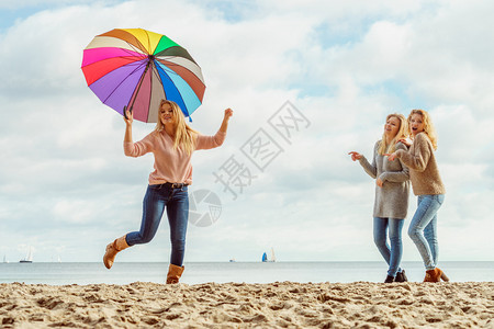 三个充满欢乐的女子在一起玩得很开心一个女人拿着多彩的雨伞女人拿着和朋友玩得开心背景图片