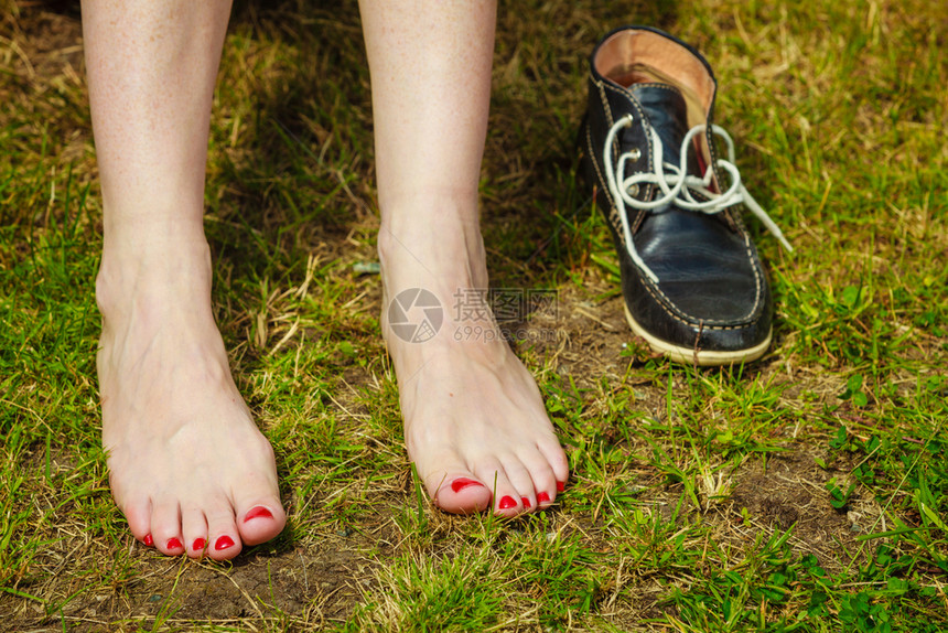 女在绿色草地上的脚紧靠她鞋子女在温暖的天气中户外放松女在绿色草地上的脚图片
