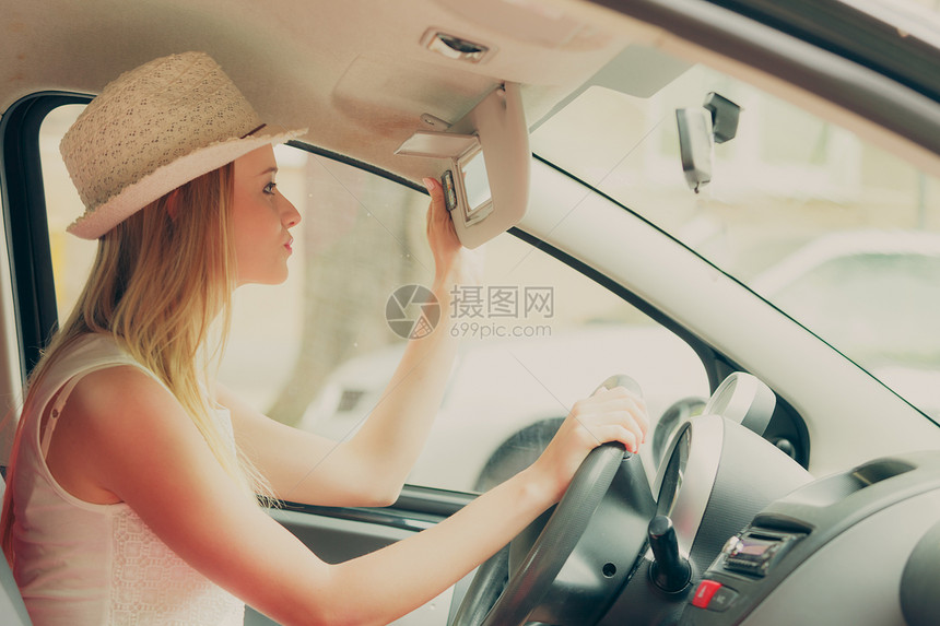 驾驶汽车时照镜子的年轻有吸引力女人图片