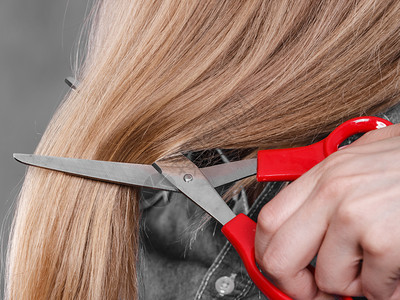 一身金发女人剪了长的直发一手红色剪刀制造现代发型一双金女人剪了头背景图片