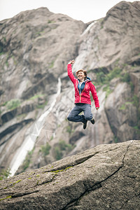 快乐的女人跳上灰山岩石享受旅行和冒险快乐女人跳上山的岩石图片