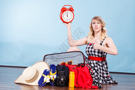 快乐的女士坐在地板上满行李的手提箱拿着大红时钟手提箱旧时钟图片