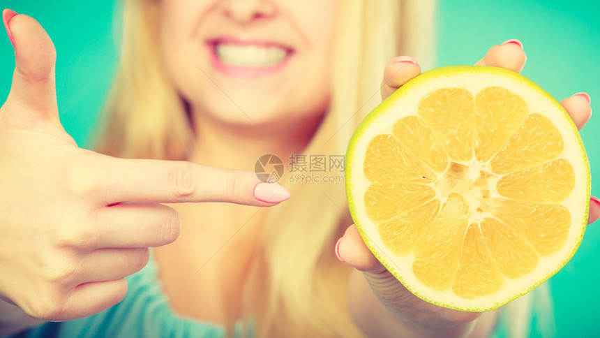 怀着一半黄葡萄果柑橘水用手指着建议健康饮食绿色微笑着的女孩图片