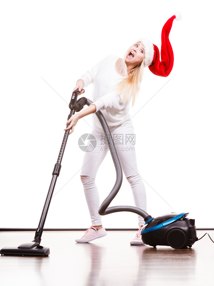 女人在屋内吸尘女孩在圣塔帮手的帽子里与吸尘器清洁工一起有趣的少女圣诞节时间和家务概念女孩与吸尘器清洁工一起在圣塔帮手的帽子里在圣图片