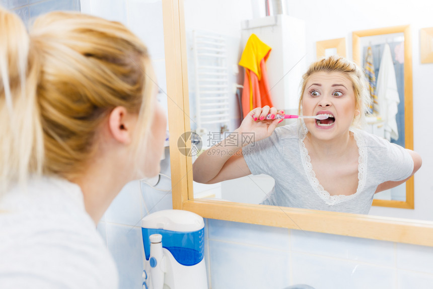 洗刷牙的女士齿的女士洗手间带牙刷的有趣金发女孩口腔卫生异常宽阔的视角洗手间刷牙的女士图片