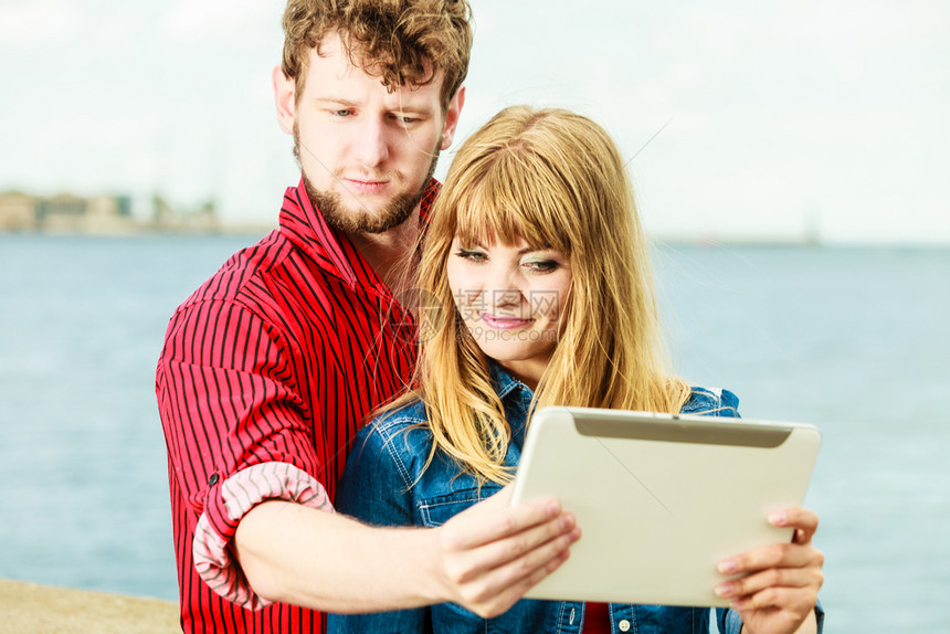 科技假日和幸福概念年轻夫妇在海边露户外用平板拍自图片