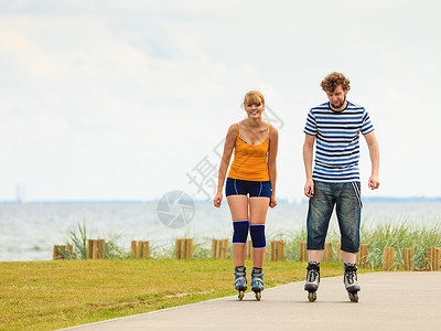 和朋友一起滑冰度假活跃的人和友谊概念穿滑溜冰雪的年轻情侣在海边户外游玩男女在赛道上一起滚车背景