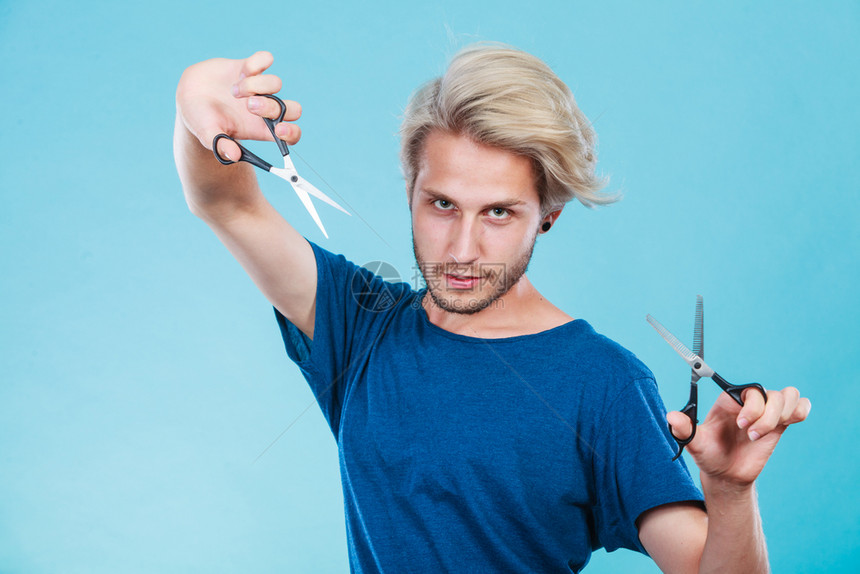 感的男理发师拿着剪刀显示工作具正常和剪图片