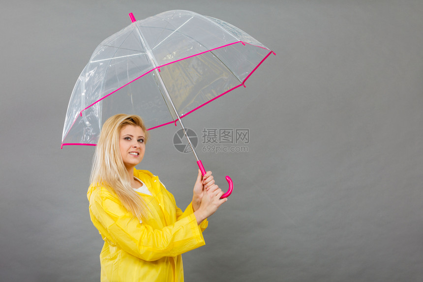 雨天时心情良好金发妇女快乐穿着黄色雨衣拿透明伞戴雨衣伞穿雨衣的妇女快乐穿着透明伞图片