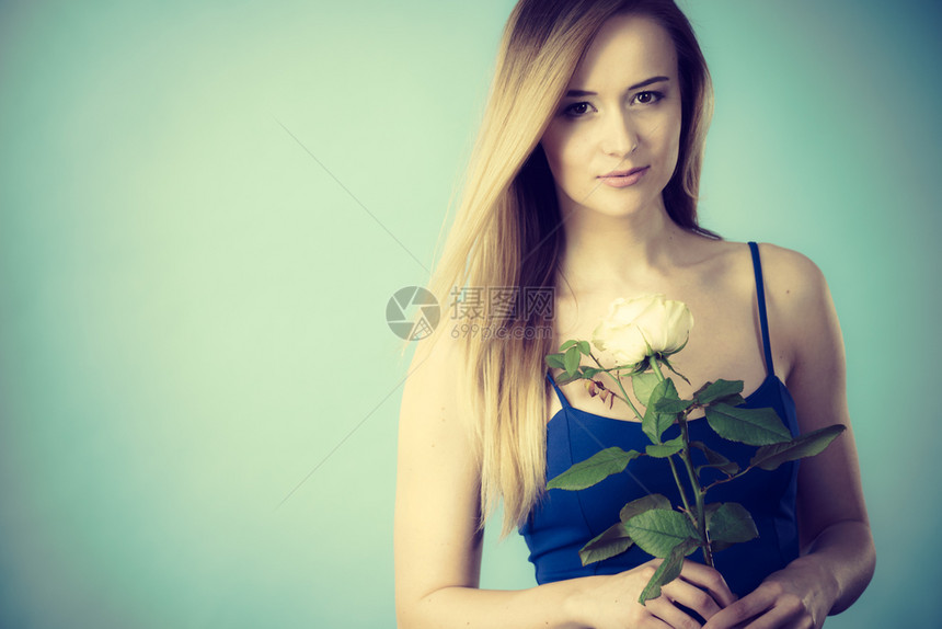 有魅力的金发年轻女子拿着白玫瑰花情人节和女礼物概念图片