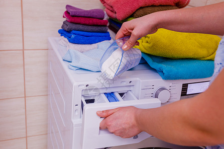 清洁机器女将洗衣粉涤剂倒入机器背景