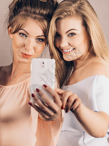 两位时尚女使用智能手机拍摄自玩得愉快地享受朋友时光图片