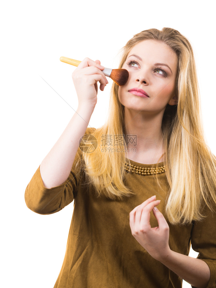 时装的年轻女子拿着专业粉刷在化妆时加了最后的触碰图片