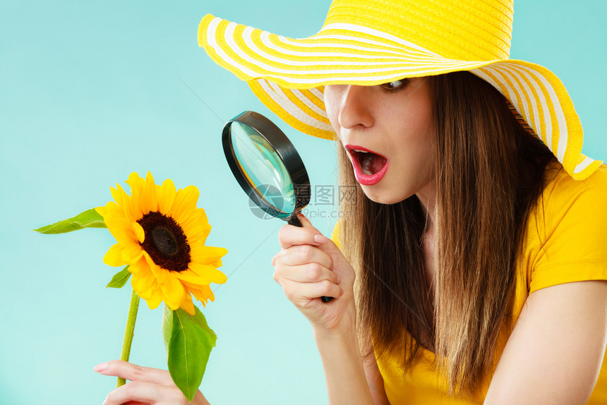植物女神惊讶地在黄色帽子检查花朵时面露图片