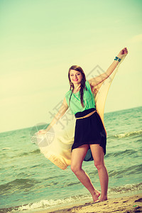 穿短多彩裙手拿着披肩跑在沙滩上玩得开心披肩在沙滩上跑的女人图片