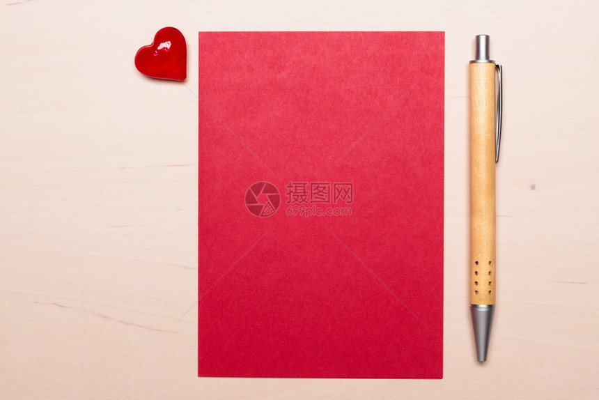 红色空白纸上面有心爱符号和木质表面的笔情人节或结婚卡的背景图片