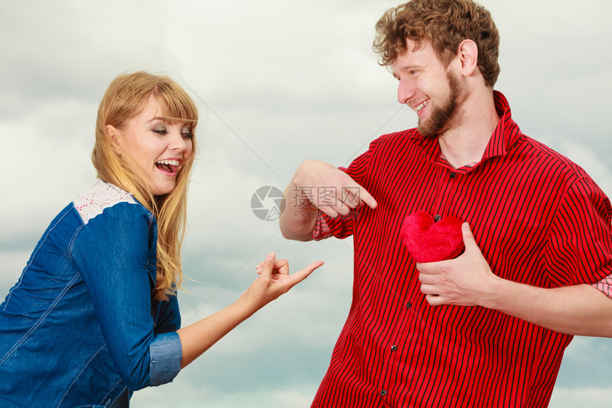爱与幸福概念男女年轻夫妇玩乐男朋友抱着胸红心爱的象征在户外与天空对立图片