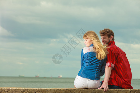 爱夫妻在海滩上共度闲暇时间坐在海滨拥抱后视线的海滩上图片