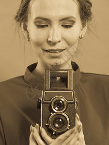 女古老风格长的深色礼服用旧相机和照片拍背景图片