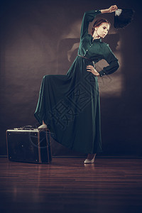 女人的旧风格长的深绿色袍旧的手提箱和羽毛风扇旧照片图片