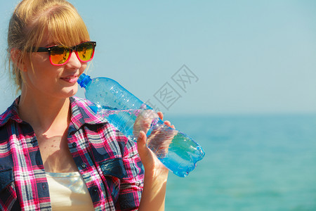 旅游女青年在背景中户外海水饮用图片