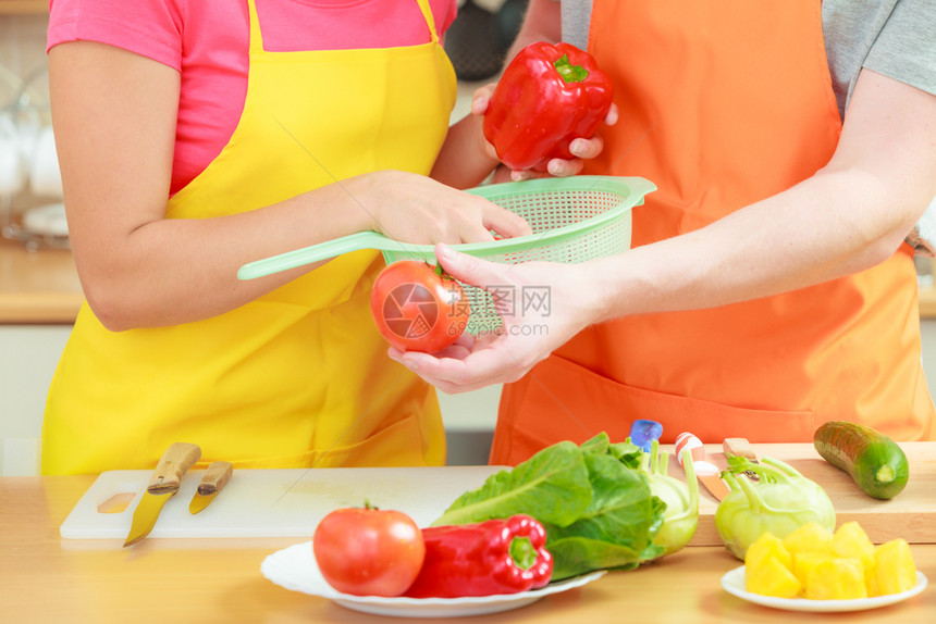 健康饮食素食烹饪节食和人们的概念幸福的年轻夫妇在家里的厨房里准备新鲜蔬菜沙拉快乐的男人和女人图片