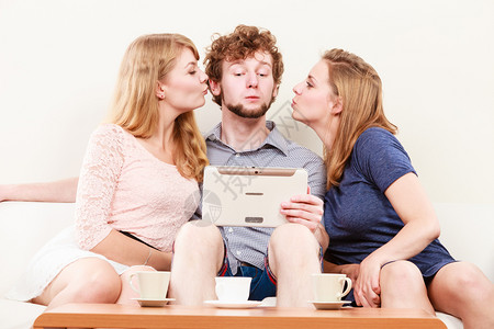 年轻女孩亲吻英俊男人平板电脑孩快乐的朋友在家放松愉快女孩亲吻男人有趣图片