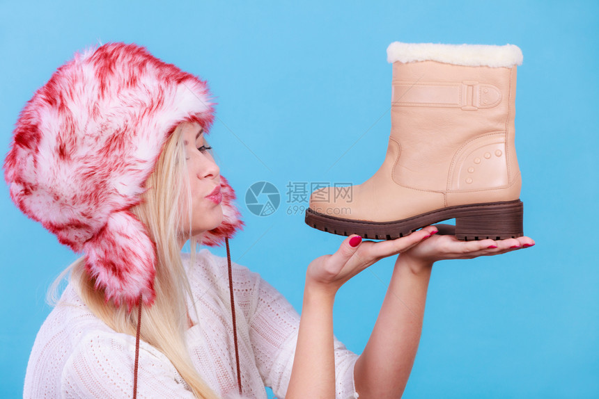 寒冷的鞋子时尚服装概念穿着毛绒冬帽的妇女穿着暖和的米色靴子穿冬帽的妇女着米色靴子图片