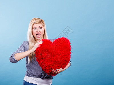 爱浪漫情人节礼物概念快乐的女士带着大红毛发枕头心型快乐的女士抱着红枕头心型背景图片